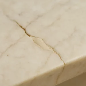 Gros plan réaliste d’un marbre ébréché restauré avec du mastic, lumière naturelle, ambiance professionnelle, fond sobre et élégant.